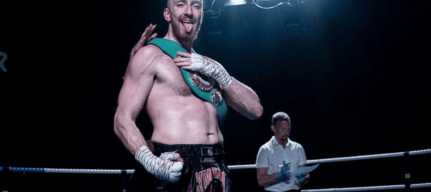 Muay Thai fighter holding a belt after winning a fight in the UK